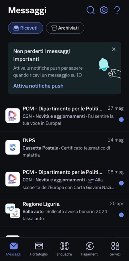 Interfaccia utente della sezione "Messaggi" dell'app IO visualizzata in modalità scura (dark mode). Nella parte superiore è presente un box informativo scuro con un'icona a forma di campanella azzurra e il testo "Non perderti i messaggi importanti - Attiva le notifiche push", accompagnato dal link "Attiva notifiche push". Sotto compare la lista cronologica dei messaggi ricevuti, tra cui notifiche della Carta Giovani Nazionale (PCM), dell'INPS (Certificato telematico di malattia) e della Regione Liguria (Sollecito bollo auto). La barra di navigazione inferiore evidenzia l'icona "Messaggi".